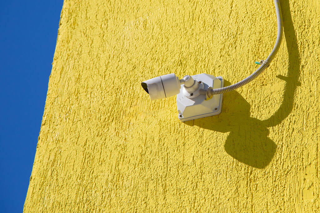 Камера видеонаблюдения на желтой стене. - Фото, изображение