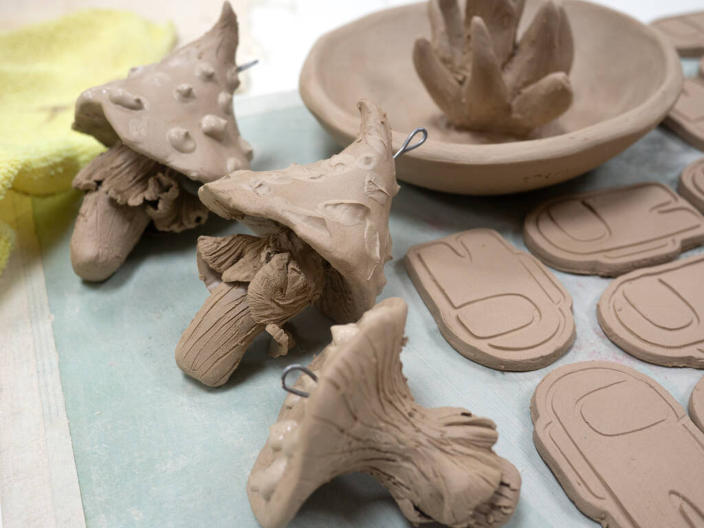 Productos creativos de arcilla hechos a mano en un estante en un taller de cerámica. Producto sin cristales y antes de cocer en el horno. - Foto, imagen