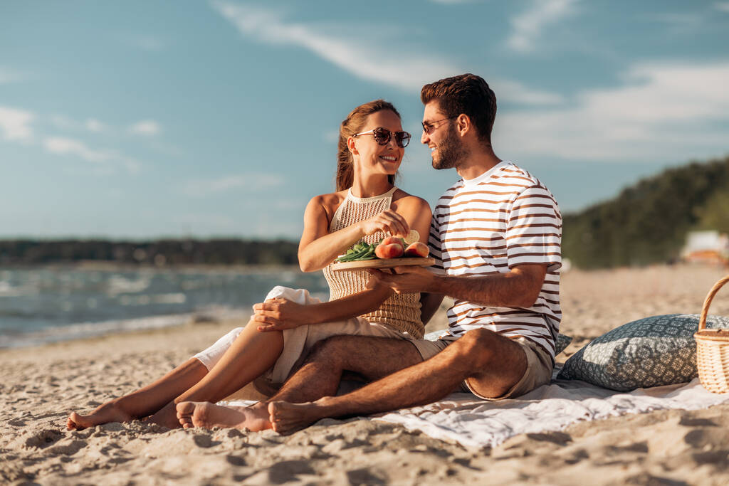 щаслива пара з їжею має пікнік на пляжі
 - Фото, зображення