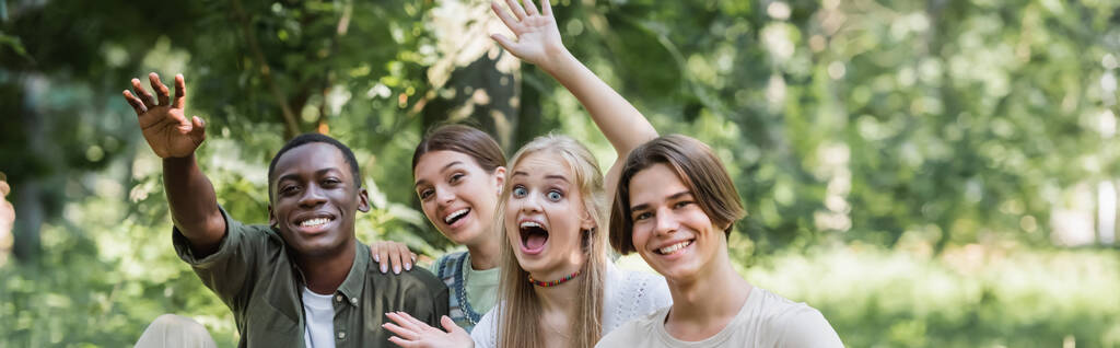 gelukkig interraciale tieners zwaaien handen op camera buiten, banner  - Foto, afbeelding