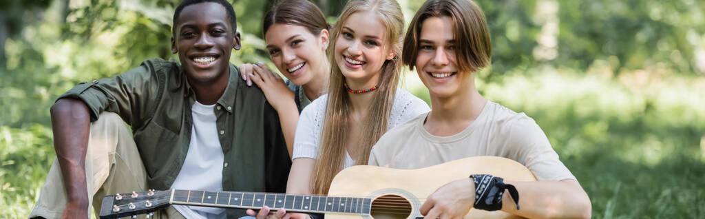 Heureux adolescents multiethniques tenant la guitare dans le parc, bannière  - Photo, image