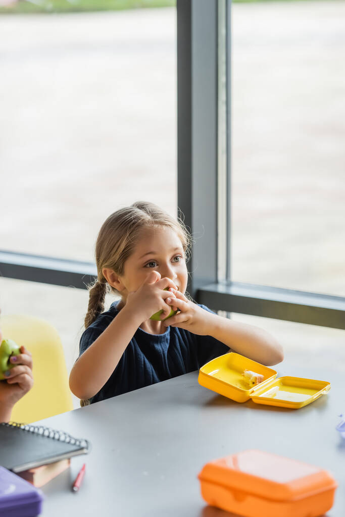schoolmeisje eten verse appel in school eetkamer - Foto, afbeelding