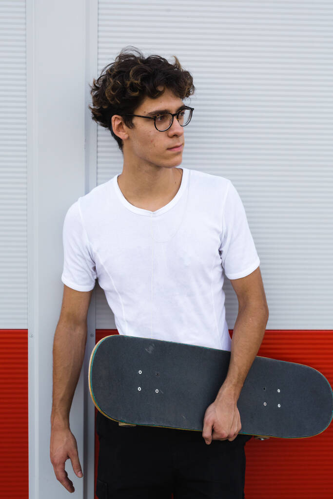 skateboarder posa contro muro rosso e bianco - Foto, immagini