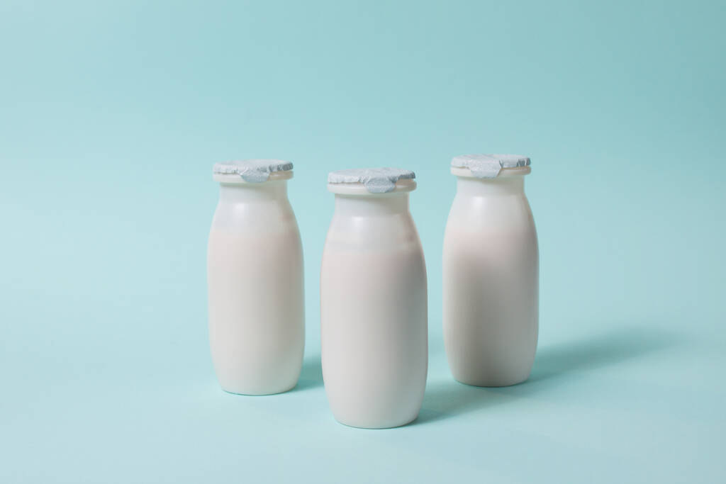 プロバイオティクスとプレバイオティクスの乳製品が入ったボトルは、水色の背景で飲みます。有用微生物とバイオヨーグルト。生物学的に活性な添加物で生産。発酵と食事｜健康食品. - 写真・画像