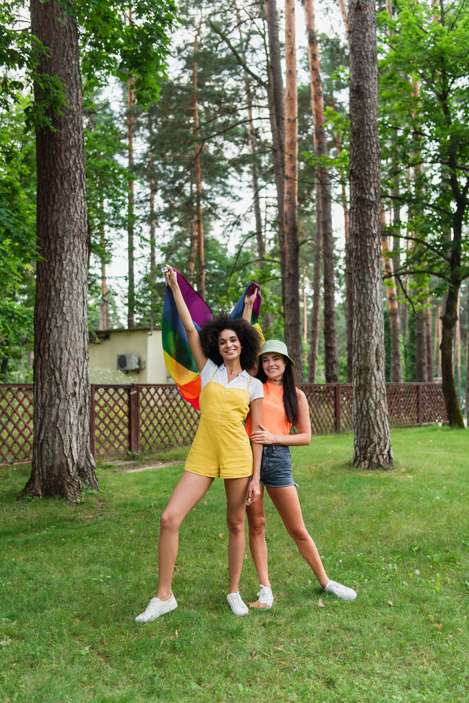 Iloinen rotujenvälinen naiset tilalla lgbt lippu puistossa  - Valokuva, kuva