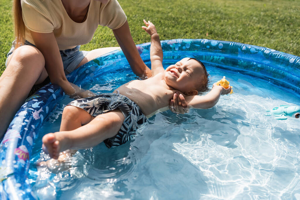 matka wspieranie dziecko syn z zamkniętymi oczami pływanie w dmuchany basen - Zdjęcie, obraz