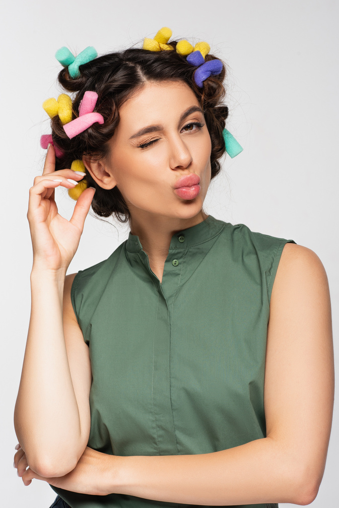 young woman with colorful hair curlers pouting lips isolated on grey - Photo, Image