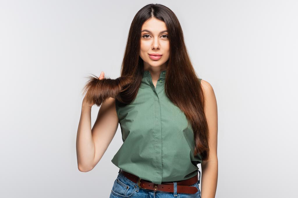 mladá žena ukazující zdravé vlasy končí izolované na šedé - Fotografie, Obrázek