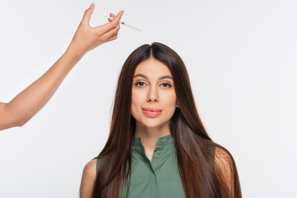 kosmetička držící stříkačku s kosmetickou výplní v blízkosti vlasů ženy izolované na šedi - Fotografie, Obrázek