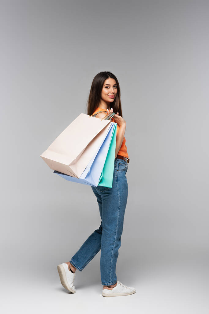 Gri renkte alışveriş torbaları taşıyan uzun boylu bir kadın.  - Fotoğraf, Görsel