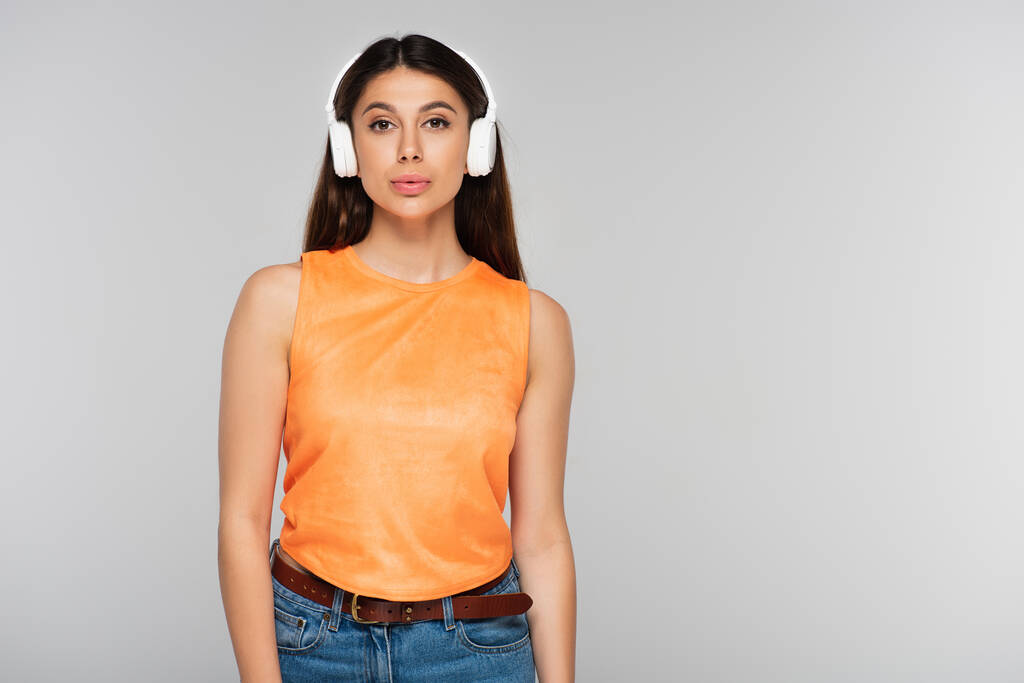 гарна молода жінка в бездротових навушниках слухає музику ізольовано на сірому
 - Фото, зображення