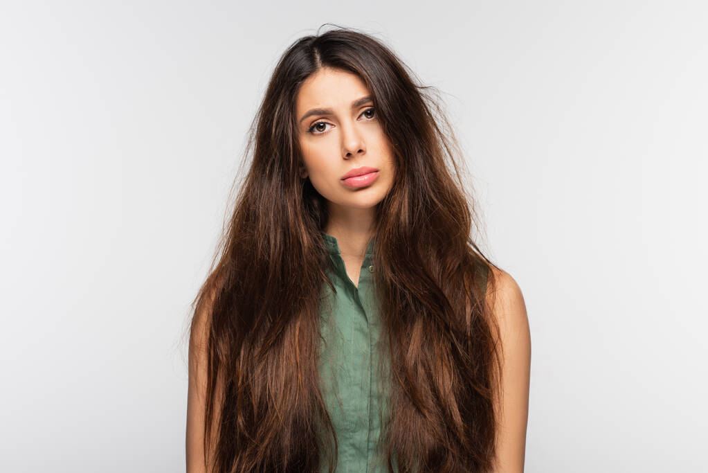 traurige junge Frau mit problematischen wirren langen Haaren isoliert auf grau - Foto, Bild