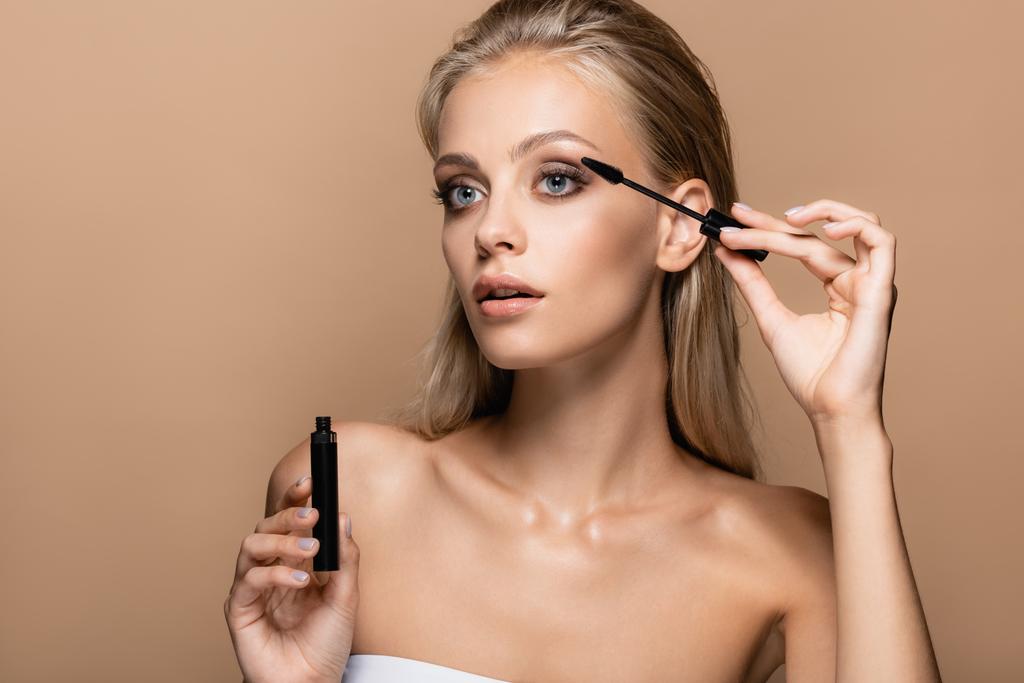 pretty woman with perfect skin applying black mascara isolated on beige - Photo, Image