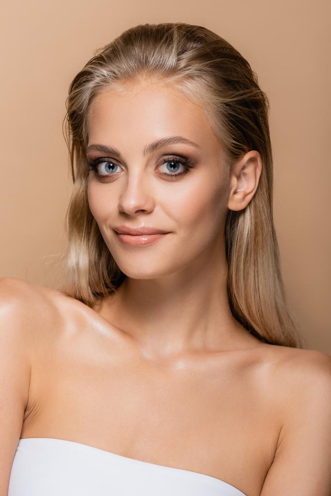 blonde woman with perfect skin and makeup smiling at camera isolated on beige - Photo, Image