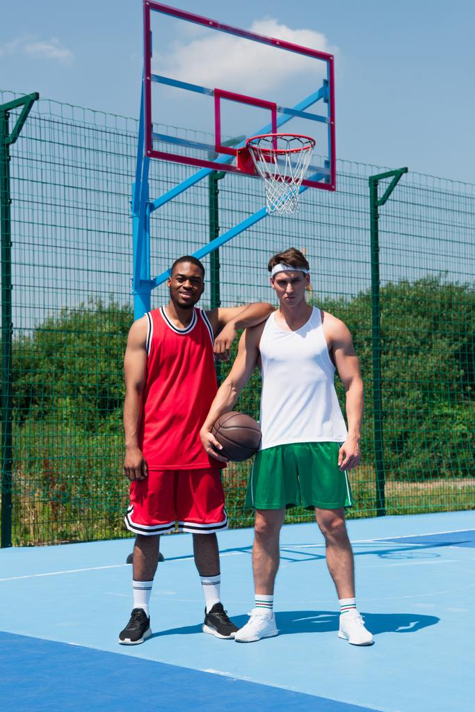 Mladí multietničtí basketbalisté při pohledu na kameru na hřišti  - Fotografie, Obrázek