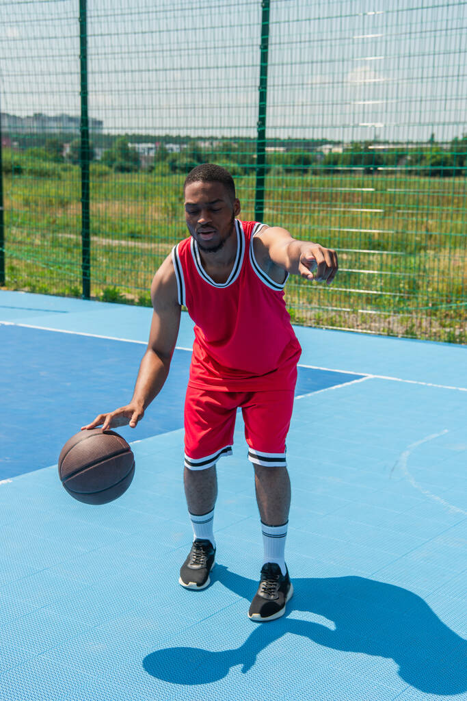 Uomo afroamericano che punta con il dito mentre gioca a streetball nel parco giochi  - Foto, immagini