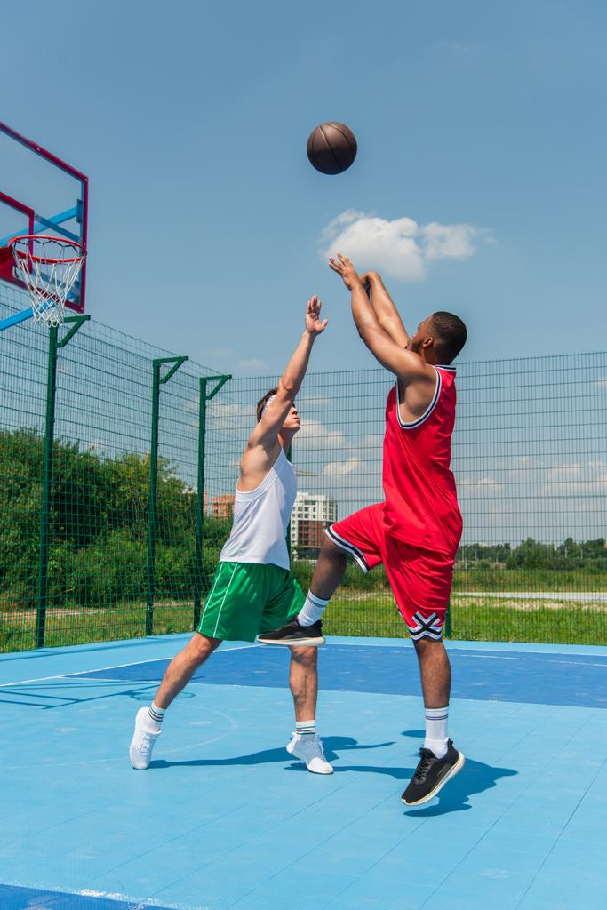 Jonge interraciale mannen spelen streetball op buiten speeltuin  - Foto, afbeelding