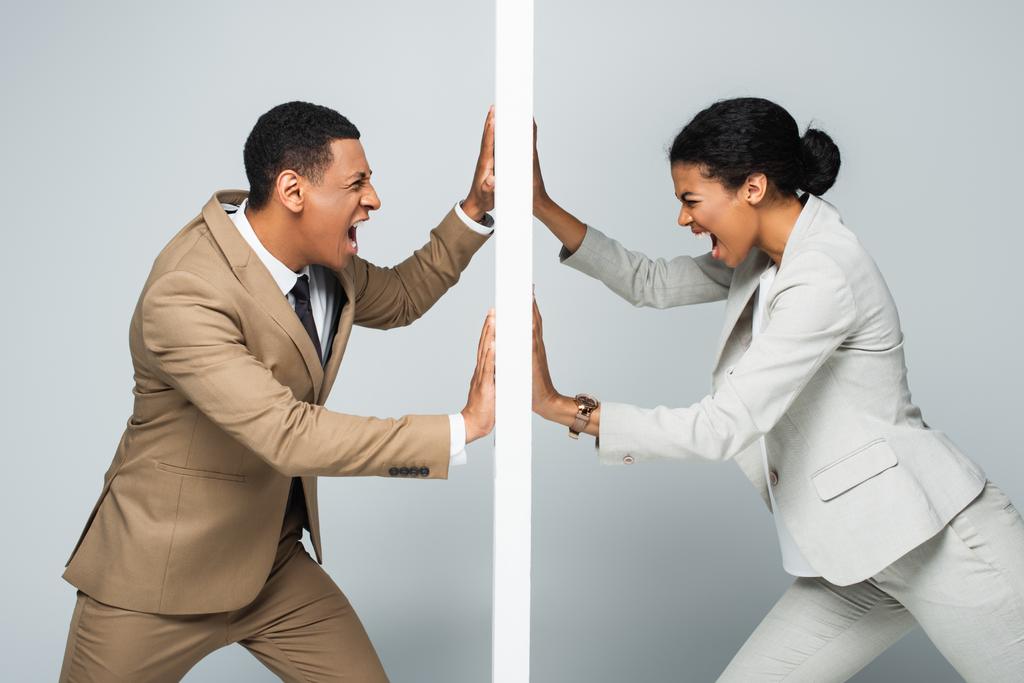 роздратований афроамериканський бізнесмен і бізнесмен тягне стіну і кричить на сіру концепцію гендерної рівності
 - Фото, зображення