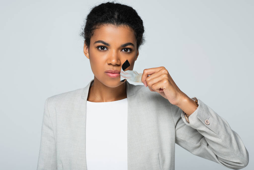 african american businesswoman taking off scotch tape on mouth isolated on grey - Photo, Image