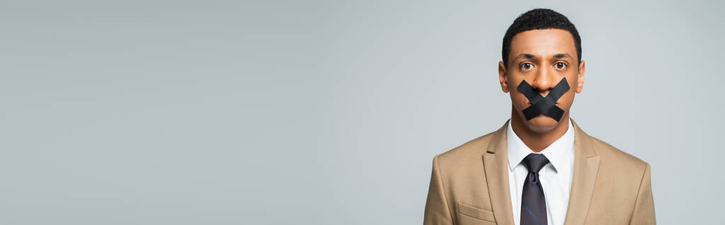 Afrikkalainen amerikkalainen liikemies, jonka suussa on teippiä harmaalla, bannerilla - Valokuva, kuva