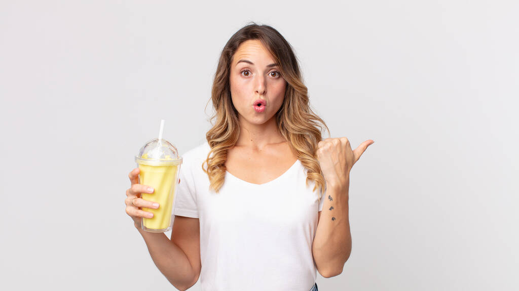 красива тонка жінка дивується в невірі і тримає ванільний молочний коктейль
 - Фото, зображення