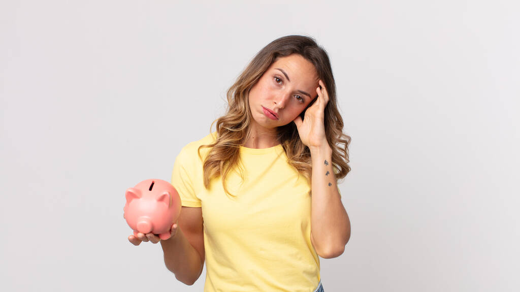 pretty thin woman feeling bored, frustrated and sleepy after a tiresome and holding a piggybank - Photo, Image