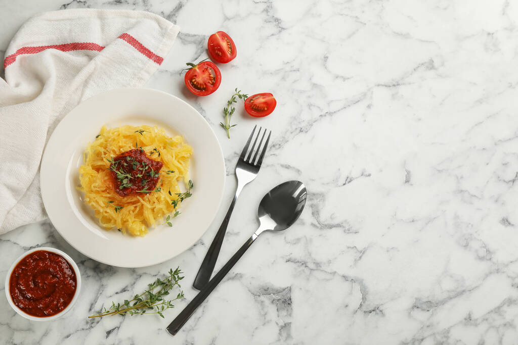 Smaczne spaghetti squash z tymiankiem i sosem pomidorowym serwowane na białym marmurowym stole, płaskie leżaki. Miejsce na tekst - Zdjęcie, obraz