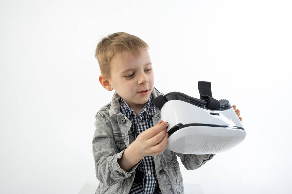 Mladý chlapec s brýlemi virtuální reality na bílém pozadí. Dítě hraje, vypadá, baví se 3D brýle. - Fotografie, Obrázek