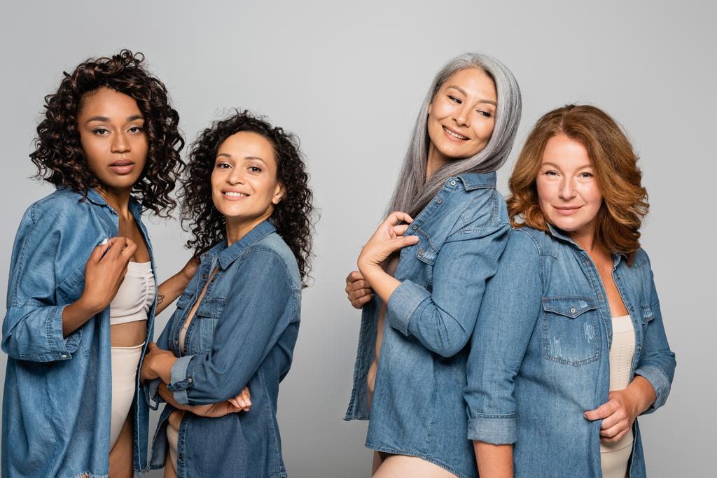 Mujeres multiculturales en lencería y camisas de mezclilla aisladas en gris, concepto positivo para el cuerpo - Foto, Imagen
