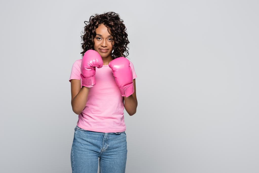Αφροαμερικανή γυναίκα με ροζ μπλουζάκι και γάντια πυγμαχίας που απομονώνονται σε γκρι - Φωτογραφία, εικόνα