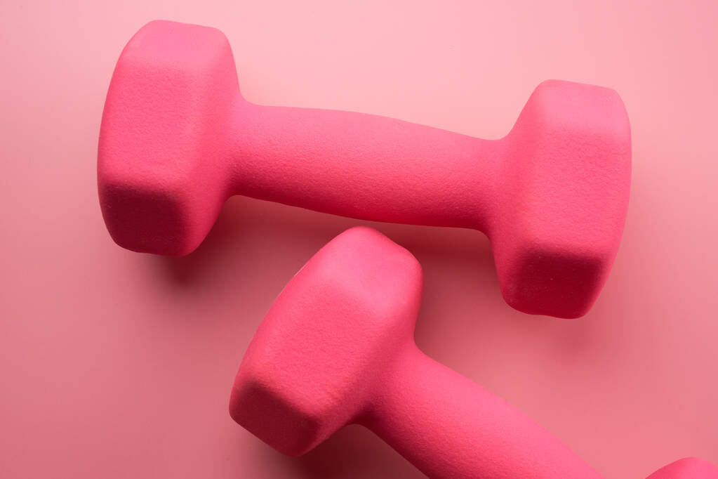 Dos pesas femeninas de color rosa aisladas sobre fondo rosa de cerca con espacio para copiar. Concepto de fitness, pérdida de peso y actividad deportiva, vista superior, cama plana - Foto, imagen