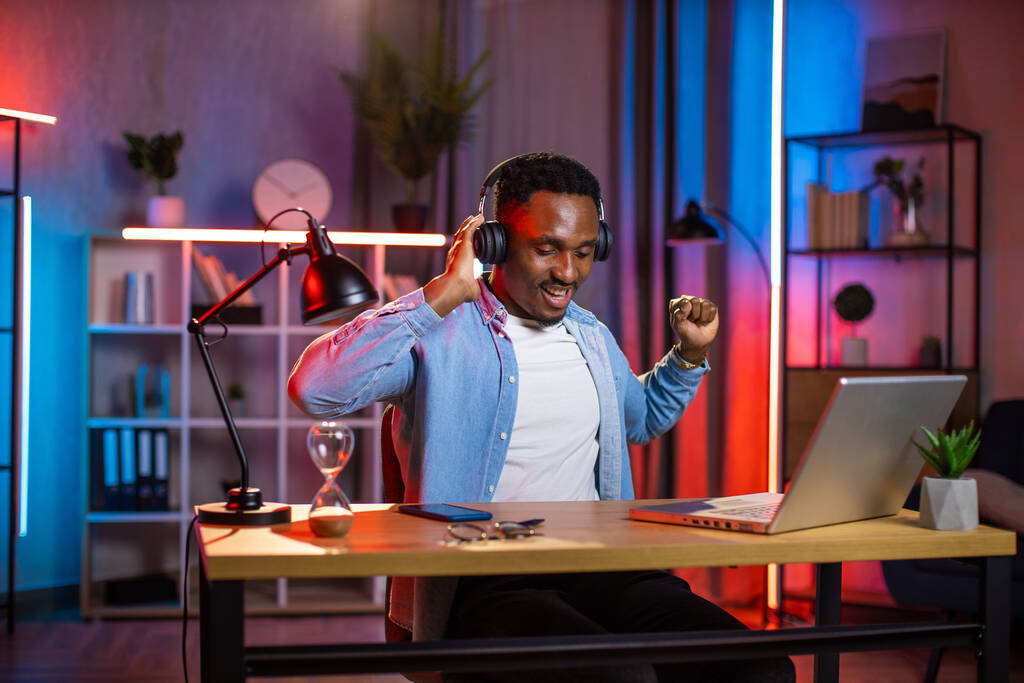 Pozytywny afrykański człowiek słuchający muzyki w słuchawkach bezprzewodowych - Zdjęcie, obraz