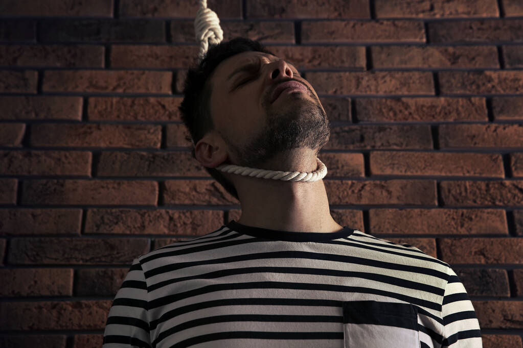 Hombre deprimido con soga de cuerda en el cuello cerca de la pared de ladrillo, vista de ángulo bajo - Foto, Imagen