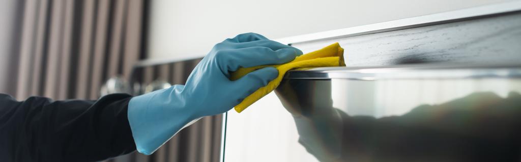 partial view of housekeeper in blue rubber glove cleaning tv display with rag, banner - Photo, Image