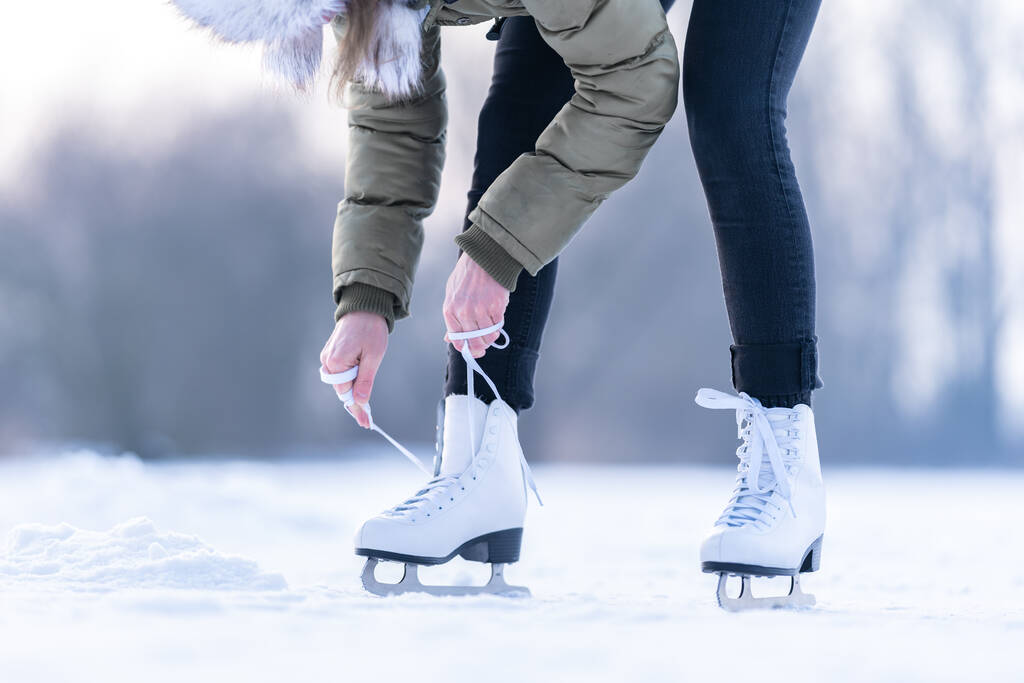 a téli korcsolyák fűzőinek megkötése egy befagyott tavon - Fotó, kép