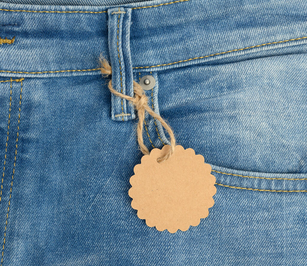 brauner Karton mit rundem Etikett, gebunden an blaue Jeans, Nahaufnahme - Foto, Bild