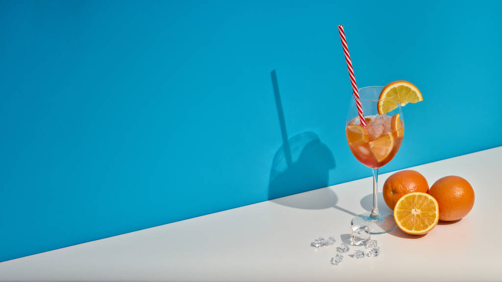 Cocktail. Bevanda di frutta con ghiaccio e arance su doppio fondo blu bianco con ombra. Ricevuto. Succo d'arancia. Sfondo banner panoramico extra ampio. - Foto, immagini