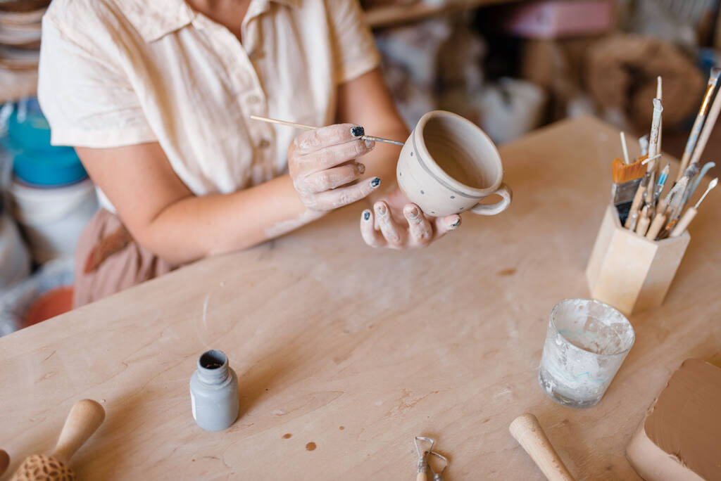 Женщина-мастер рисует горшок, мастерскую по гончарному делу. Женщина, литье миски. Керамика ручной работы, глиняная посуда - Фото, изображение