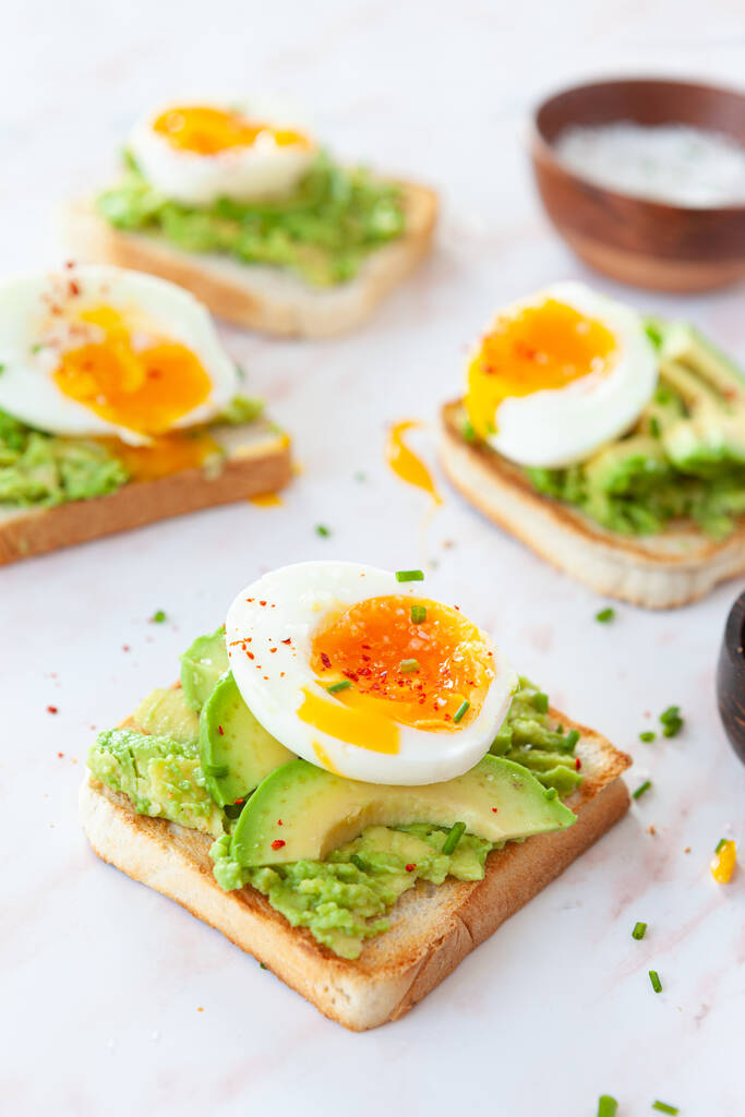 szendvics avokádóval, tojás és pirítós tojással, paradicsommal és bazsalikommal. egészséges reggeli. - Fotó, kép