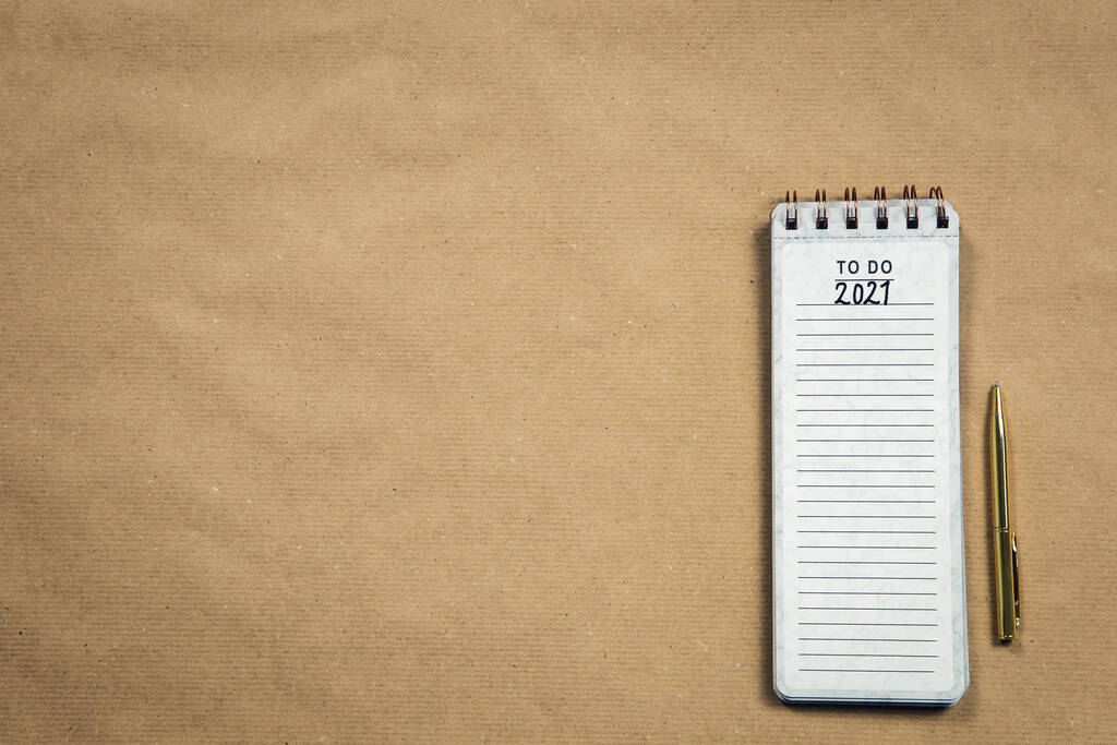 Planning New Year goald on empty notepad in the year 2021, top view on brown background texture, top view copy space, space for text modern design close-up - Photo, Image