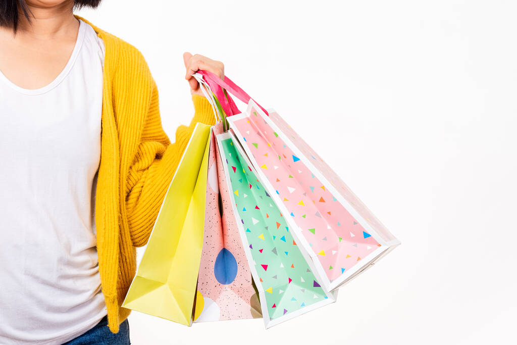 Šťastná žena ruka nosí žlutou košili drží nákupní tašky multicolor, mladá žena držet mnoho balíčků v náručí izolované na bílém pozadí, Black Friday prodej koncept - Fotografie, Obrázek
