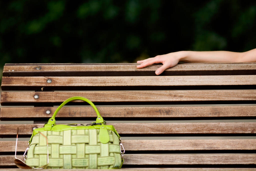 žena ruka drží dřevěný koš se slámou taška na zeleném travnatém pozadí - Fotografie, Obrázek