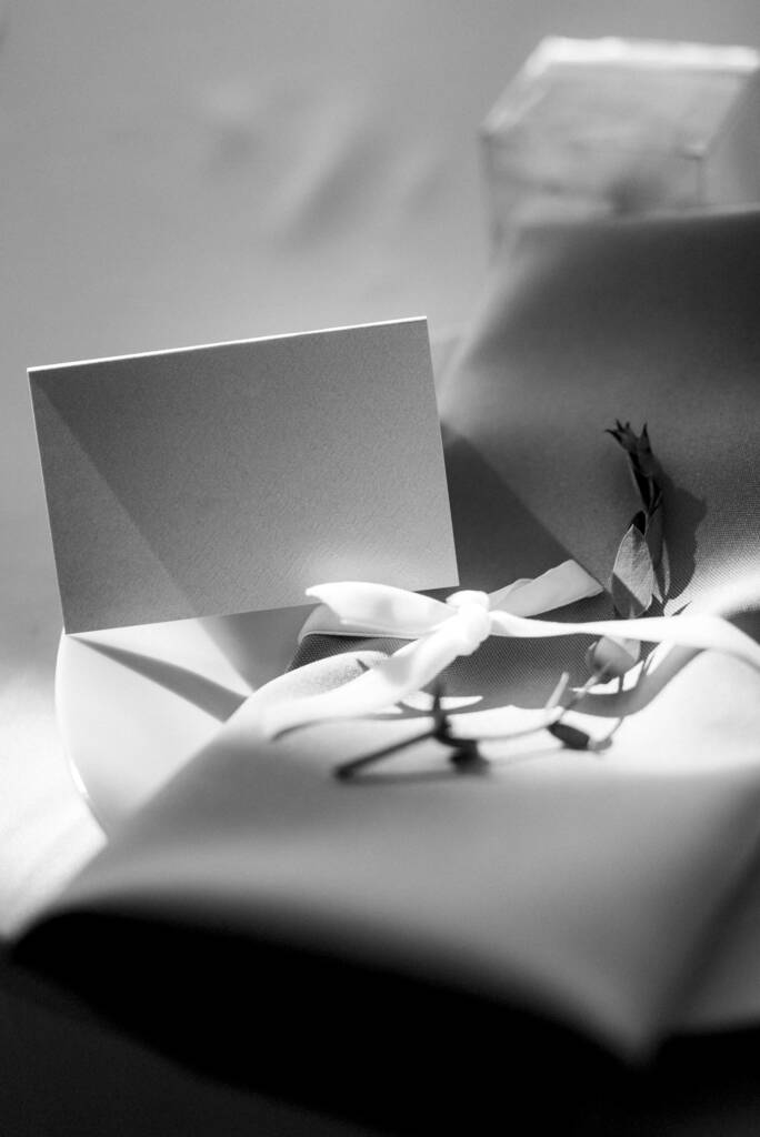 wit papier geschenkdoos met een strik en een zwart lint op een grijze achtergrond - Foto, afbeelding