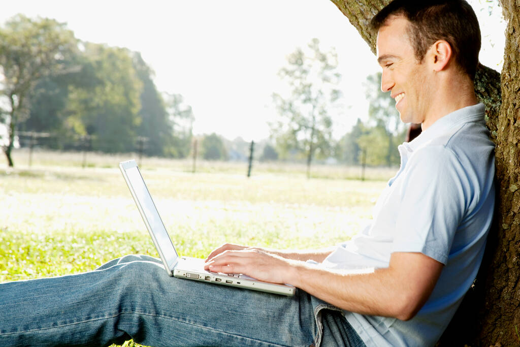 joven sentado en la hierba y el uso de ordenador portátil - Foto, imagen