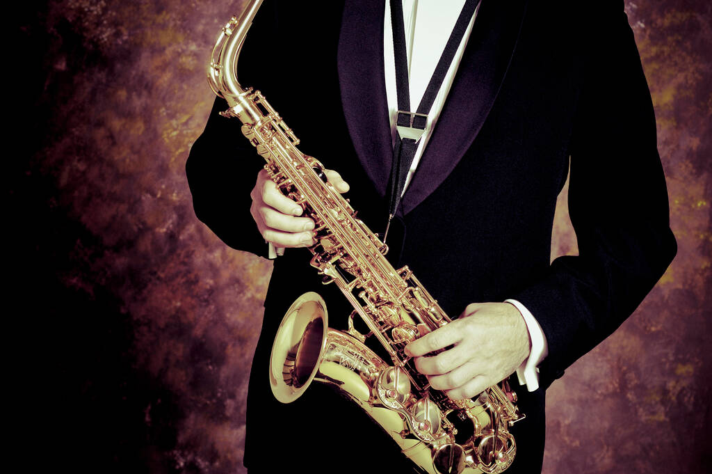 man spelen saxofoon op een zwarte achtergrond - Foto, afbeelding