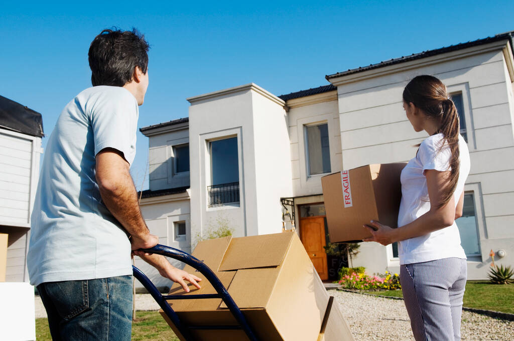 pareja de cajas de desembalaje con caja de cartón y el hombre en frente de la nueva casa - Foto, imagen
