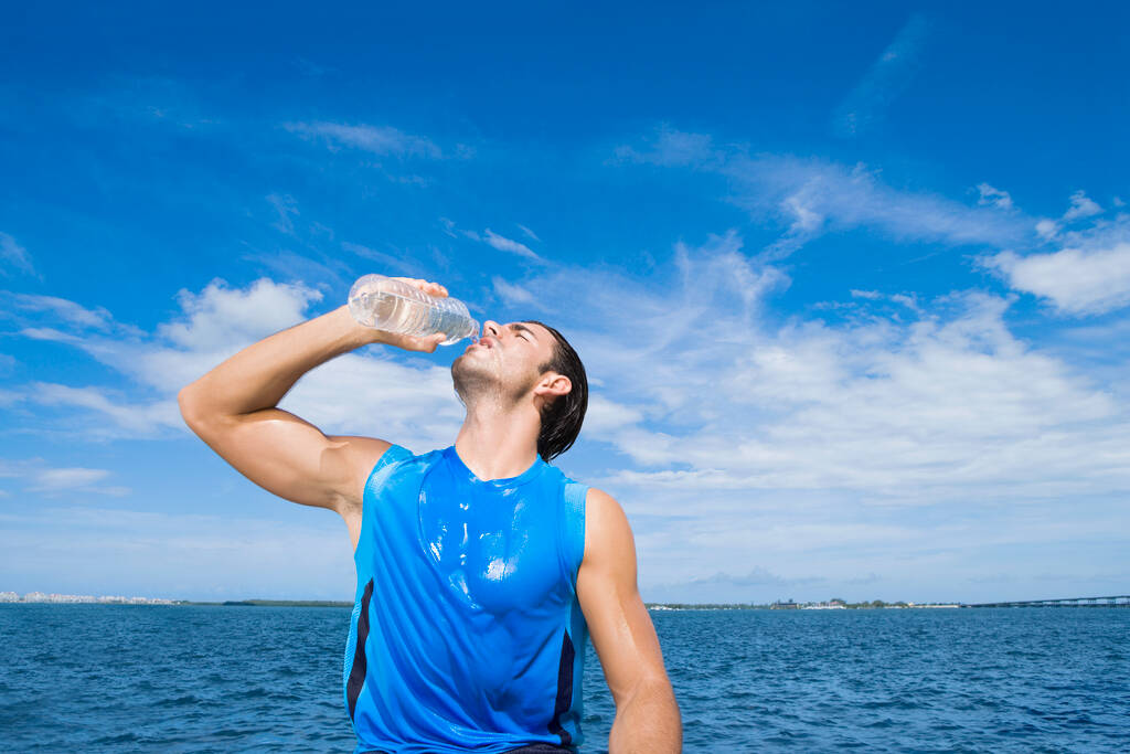 человек с бутылкой воды на пляже - Фото, изображение