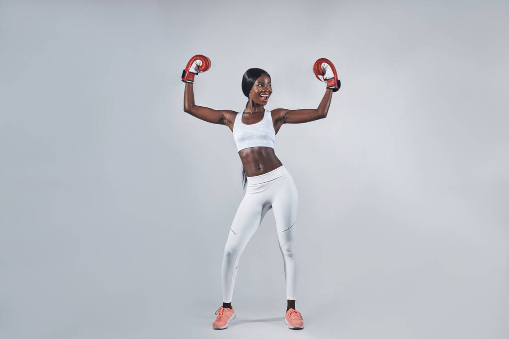 Schöne junge Afrikanerin in Boxhandschuhen mit erhobenen Armen - Foto, Bild