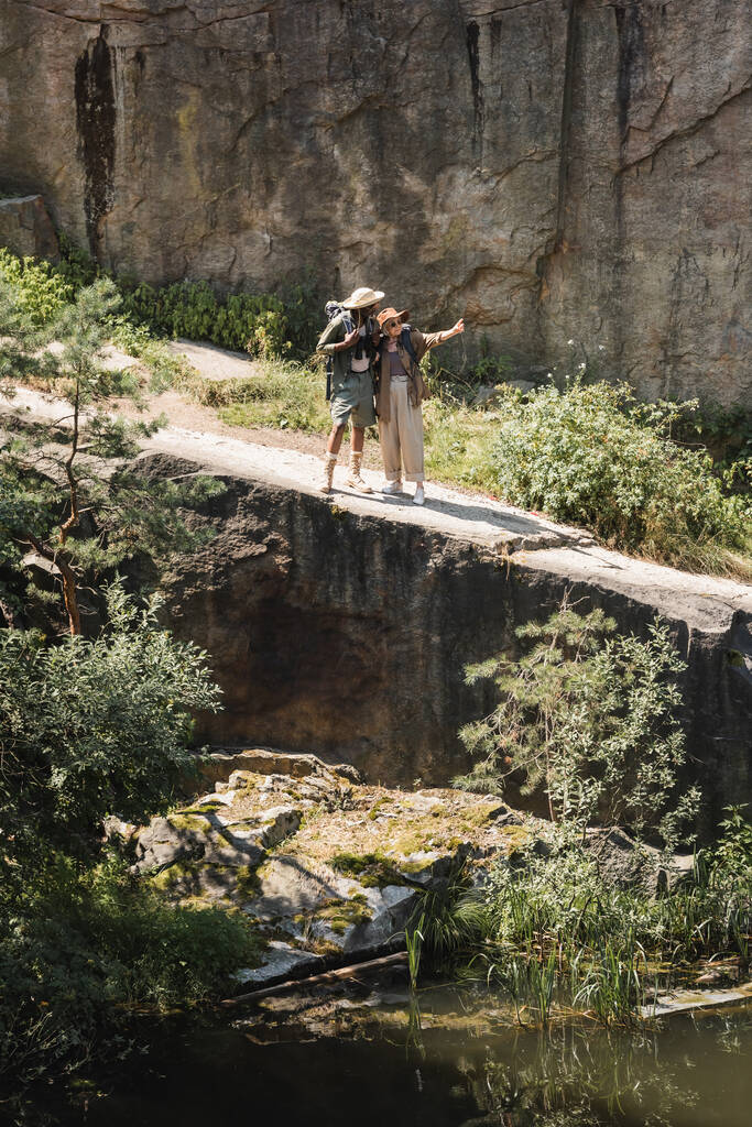 Старший путешественник указывает пальцем на африканского американского мужа и скалу  - Фото, изображение