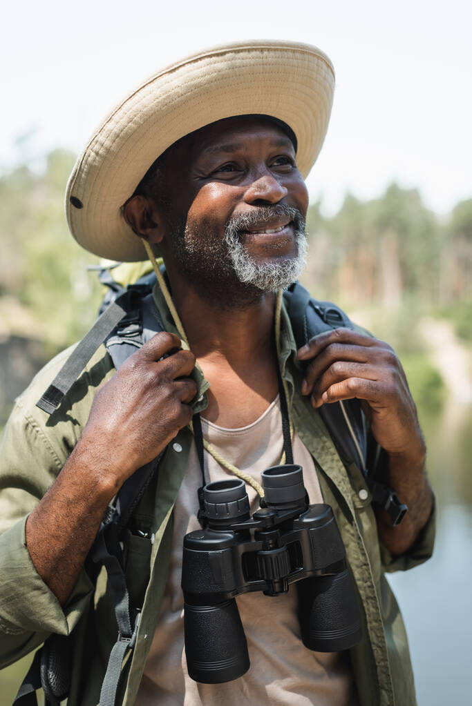 Dürbünlü ve sırt çantalı mutlu Afrikalı Amerikalı turist.  - Fotoğraf, Görsel